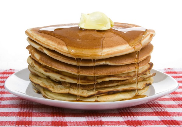 Delicious stack of pancakes with butter and syrup on a red checked table cloth